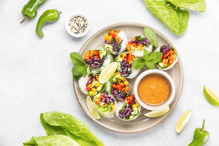 Vegan rainbow-colored spring rolls served with peanut sauce, top down viewの写真素材
