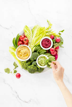 Fresh green veggie platter with various dips, top-down view, spring easy snack recipe ideaの写真素材
