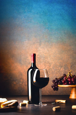 Bottle of red wine and a glass full of wine served for tasting with snacks, front viewの写真素材