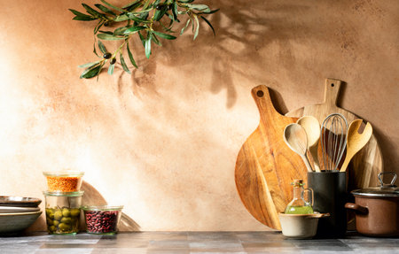 Kitchen utensils put on a warm rustic home kitchen countertop lighten up by sun rays, front view, copy space for a textの写真素材
