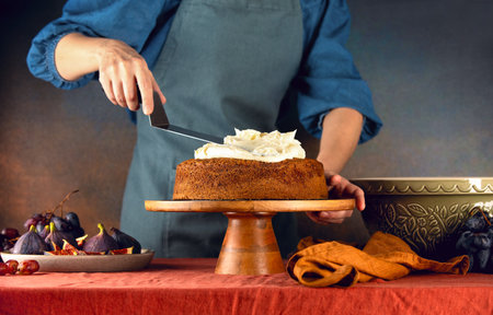 Woman is decorating fall pumpkin spice sponge cake with  buttercream toppingの写真素材