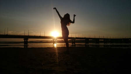 Girl on the background of sunset on the bridgeの写真素材