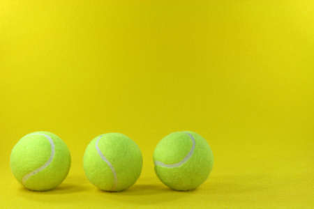 three yellow tennis balls in the left side with yellow background sports conceptsの写真素材