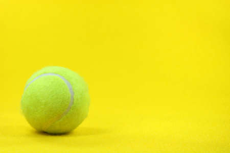 one yellow tennis ball in the left side with yellow background sports conceptsの写真素材