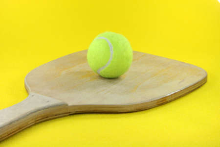 beach wooden racket with yellow ball in yellow background prespectiveの写真素材