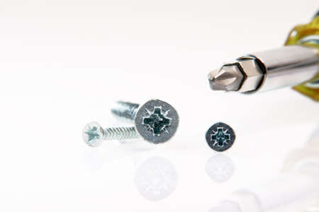 screwdiver detail and screws on white background industrial and construction tools with big copy space and small reflectionの写真素材
