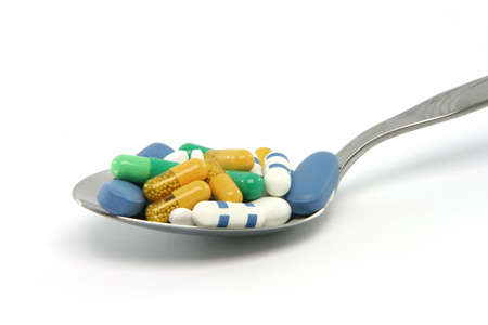 spoon full of pills isolated on white background health amd medical concepts