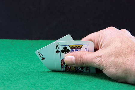 hand holding ace and king closeup on green felt background and black copyspaceのeditorial素材