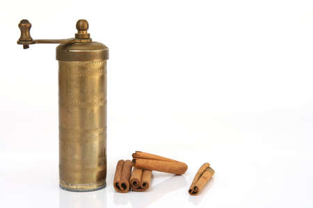 antigue kitchen hand mill with cinnamon  isolated on white background の写真素材