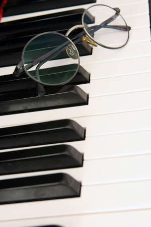spectacles on piano keyboard detail music and arts conceptsの写真素材