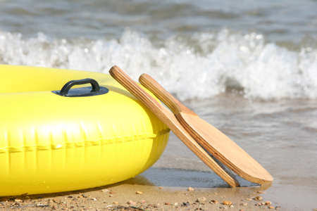 detail yellow inflatable by the sea and wooden beach tennis racketsの写真素材