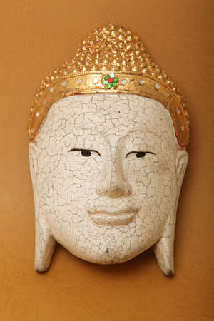 handcrafted wooden buddha face decorative mask on yellow background の写真素材