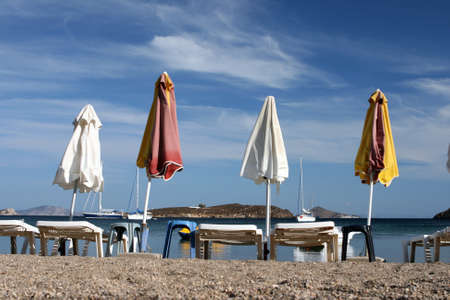 empty beach chairs and umbrellas and cloudy blue sky copyspaceの写真素材