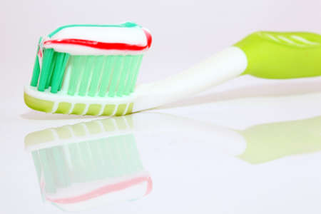 tooth paste on green brush closeup with beautiful reflection on whiteの写真素材