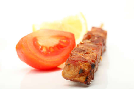 pork kebap on wooden stick grilled isolated with tomato and lemonの写真素材