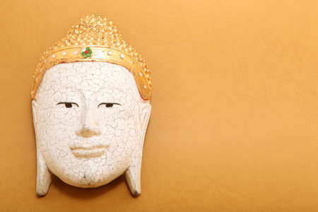 handcrafted wooden buddha decorative mask on yellow background with copyspaceの写真素材