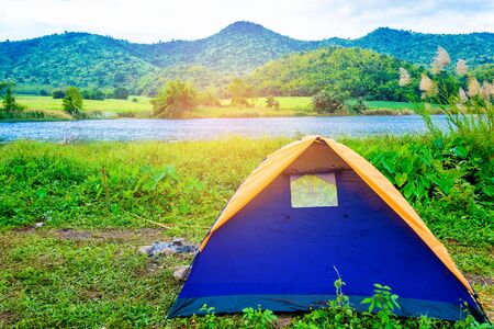 Tent in the woods beside the river on vacation at morningの写真素材