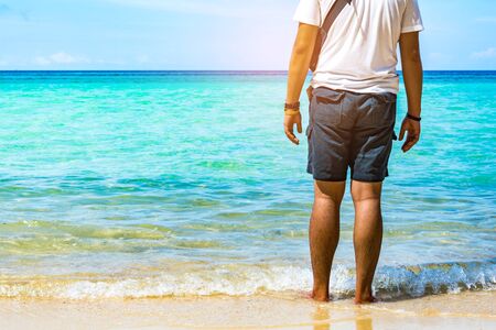 People standing in the sea. Blue sea and a moving reflection of sunlight . White sandy beach on...