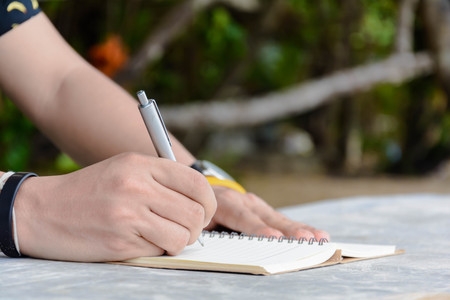 Man writing pen in book on vacation