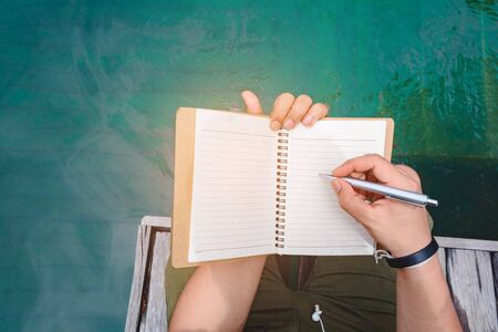 Man writing pen in book on vacationの写真素材