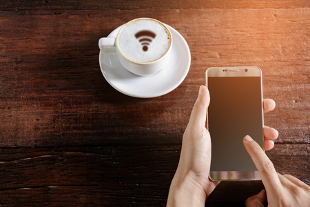 coffee cup wifi and good morning .cellphone in hand on wood tableの写真素材