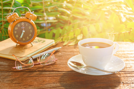 coffee cup clock and news paper on old wooden table the good morning