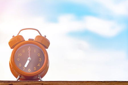 Brown clock on an old wood table Natural backgroundの写真素材