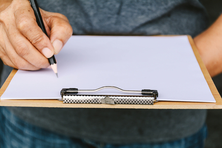 People are writing a message on it paper on clipboard at daytimeの写真素材