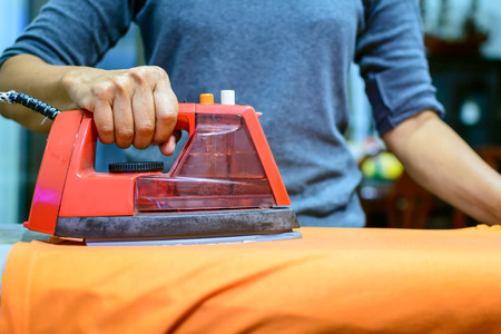 Woman ironing clothes in home at nightの写真素材