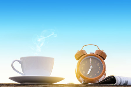 coffee cup clock and news paper on old wooden table nature background the good morning