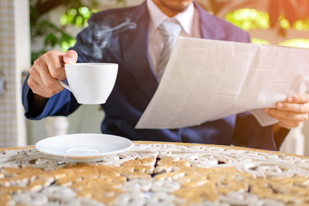 Male businessmen read newspapers and drank black coffee early in the morning at the homeの写真素材