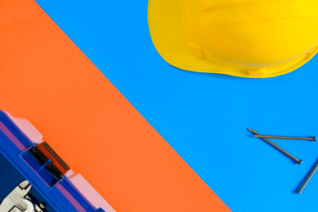 yellow safety helmet and Construction materials on paper blue and orange with color contrast and top viewの写真素材