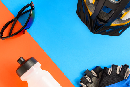 set bicycle equipment on a blue and orange paper background with healthy sportsの写真素材