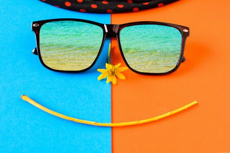 Sunglasses and hats on colorful blue and orange paper with Face smile and relax timeの写真素材
