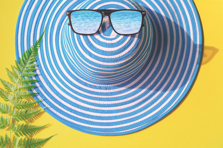 Blue hat and sunglasses on colorful paper with travel and fashion styleの写真素材