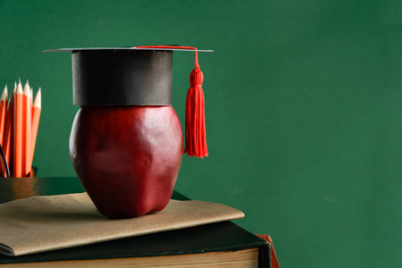 graduate cap and apple on old book at library green wall background with learning and study education.selective focusの写真素材