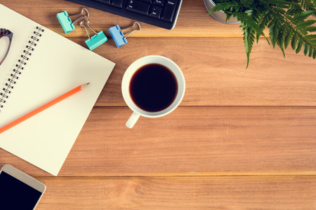 top view desk wood and office equipment with hot tea afternoon and decorative treeの写真素材