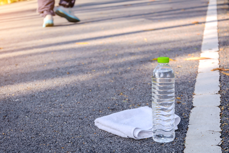 Plastic water bottle and white cloth on desk with running exercise people at the park.の写真素材