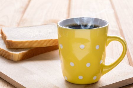Good morning black coffee cup and bread on a wooden table in the sunrise background. breakfast and wake upの写真素材