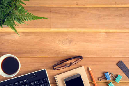 top view desk wood and office equipment with hot tea afternoon and decorative treeの写真素材