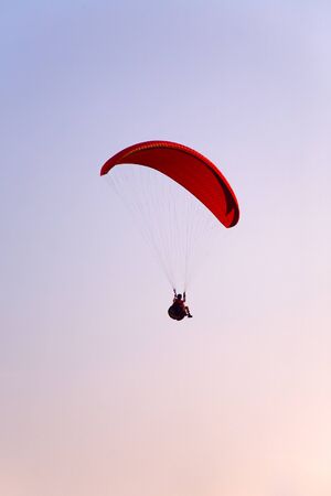 Paraglider final approach before landing in the evening skyの写真素材