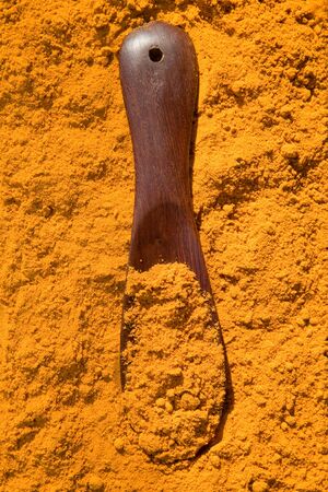 Turmeric powder spice pile with spoonの写真素材