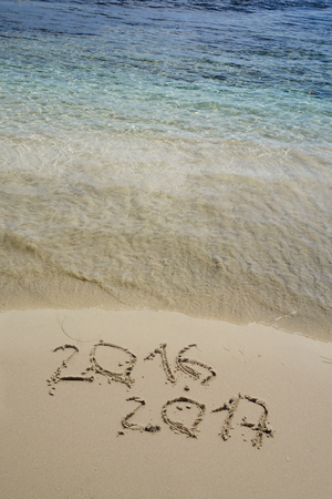 new year numbers 2016 and 2017  drawings in the sand on the beachの写真素材