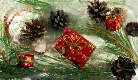 Background of   red  beads and craft  Christmas gift , cone,  twig of pine tree  in ice   cube with air bubbles.Happy new year 2019 greeting card . Copy space, top view,  flat layの写真素材