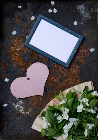 Valentine's Day card with wooden  pink heart , flower of apple with fan of handmade paperwork  and frame against textured rustic iron  backgroundの写真素材