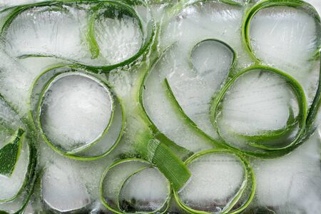 Background skin and piece of  fresh szucchini frozen in iceの写真素材
