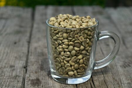 green coffee beans with with glass cup and green leaves, close-upの写真素材