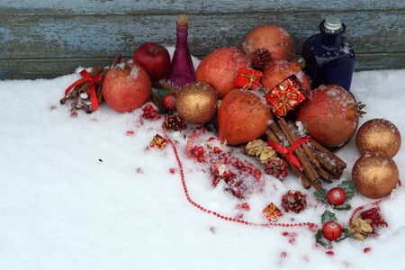 Fresh pomegranate with cinnamon, red ball, gift boxes in craft paper   and on    snow as background. Christmas and New year decorations or greeting card.の写真素材