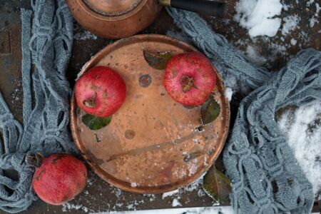 Fresh red  pomegranate on copper tray   with gray scarf as Christmas decor over iron  backgroundの写真素材