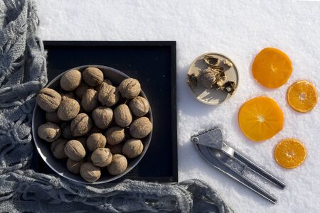 winter flat lay with  walnut on black tray,   cracked nut with nutshell, Nutcracker, ebony,...